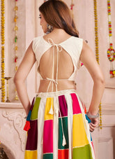 Woman wearing a colorful skirt with an open-back top against a decorative wall.